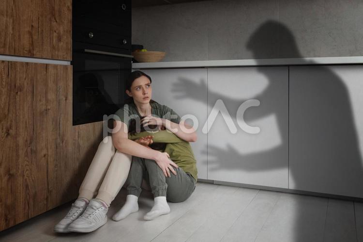 怒っている男性のシルエットと男の子を抱きしめる女性 親子,母親,男の子の写真素材