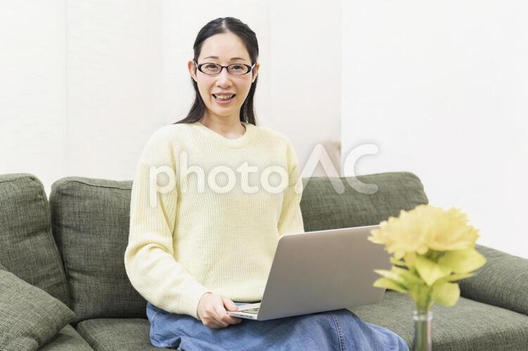 ソファーでノートパソコンを使う女性 ソファー,ノートパソコン,女性の写真素材