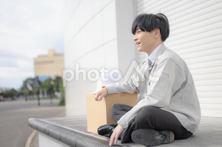 倉庫の前で座る作業員男性 笑顔,男性,作業服の写真素材