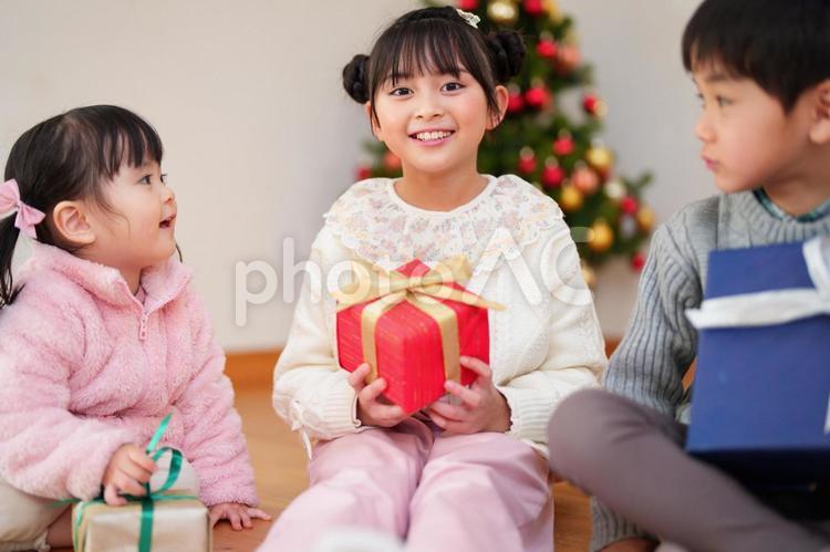 プレゼントを持ち座っている子供たち 男女,クリスマス,笑顔の写真素材