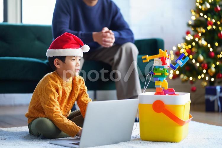 座ってパソコンする男の子と横におもちゃとクリスマスツリー 男の子,小学生,親子の写真素材