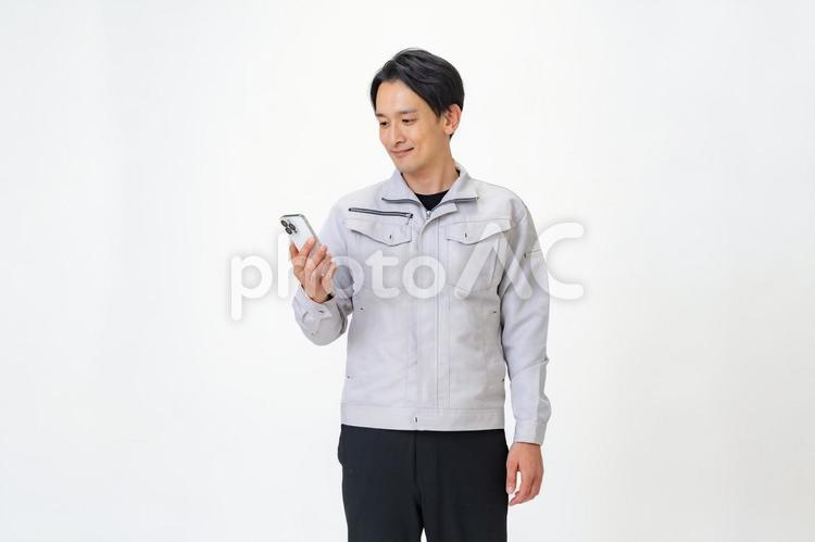 携帯を見る作業着を着た男性 日本人,点検,保守点検の写真素材
