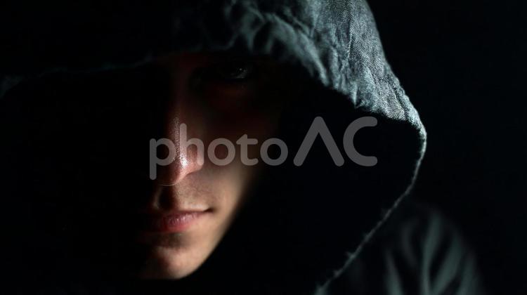フードをかぶり暗闇に潜む謎の人物 シルエット,フード,男の写真素材