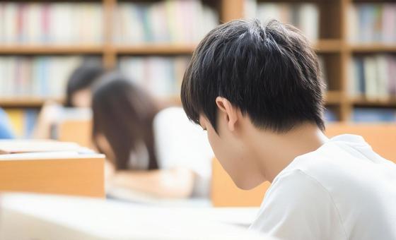 図書室で真剣に勉強する小学生男子 図書室で真剣に勉強する小学生男子の写真