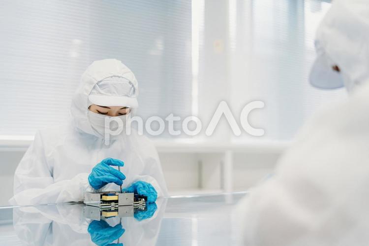クリーンルームで精密機器を扱う女性 工場,製造業,精密機器の写真素材