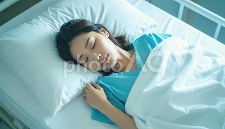 片腕の下にバスタオルを置いて眠る女性患者 バスタオル枕,首こり,背中の写真素材