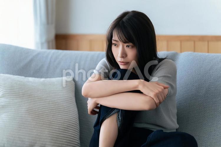 ソファに座って考えごとをする女性 女性,考える,困るの写真素材