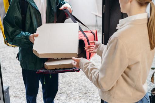 保温ピザバッグ出したピザを女性に渡しているフードデリバリーの男性 配達,フードデリバリー,デリバリーの写真素材