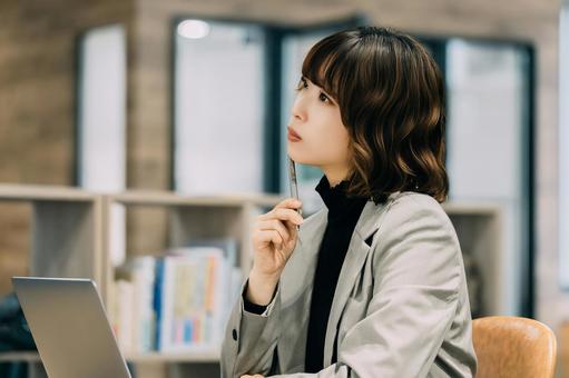 パソコンを使いながら考えごとをする女性 パソコンを使いながら考えごとをする女性 女性,パソコン,考えるの写真素材