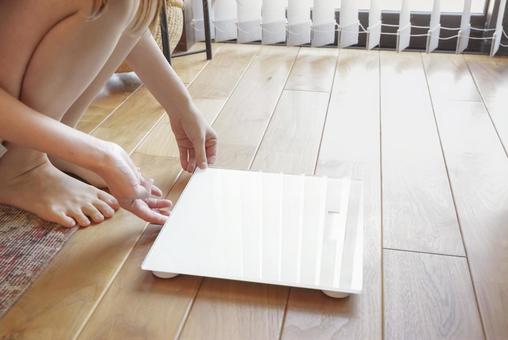 体重計で体重の計測をする女性 体重計で体重の計測をする女性の写真