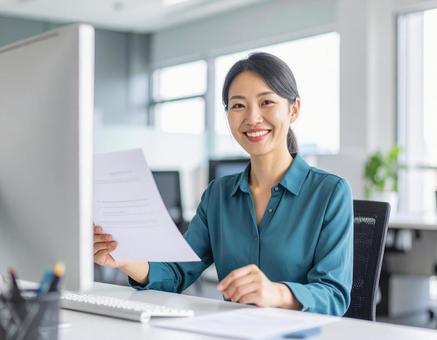 書類を手に笑顔を見せる女性 書類を手に笑顔を見せる女性の写真