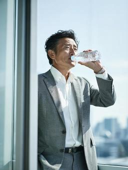 水分補給をする日本人ビジネスマン 水分補給をする日本人ビジネスマンの写真