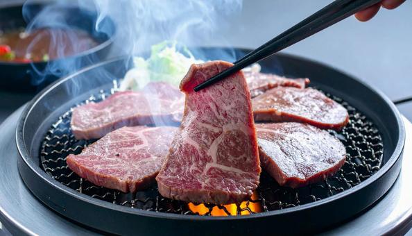 焼肉を鉄板で焼いて鉄箸ですくう 焼肉を鉄板で焼いて鉄箸ですくうの写真