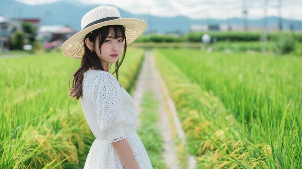 田園風景の道を歩くワンピース姿の女性 田園風景の道を歩くワンピース姿の女性の写真