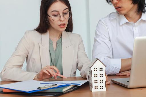 家の模型を前に仕事をする男女 保険業,事務職,接客業の写真素材