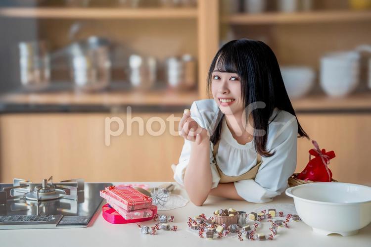 チョコの粒をつまむ若いエプロン姿の女性 バレンタイン,バレンタインデー,チョコの写真素材