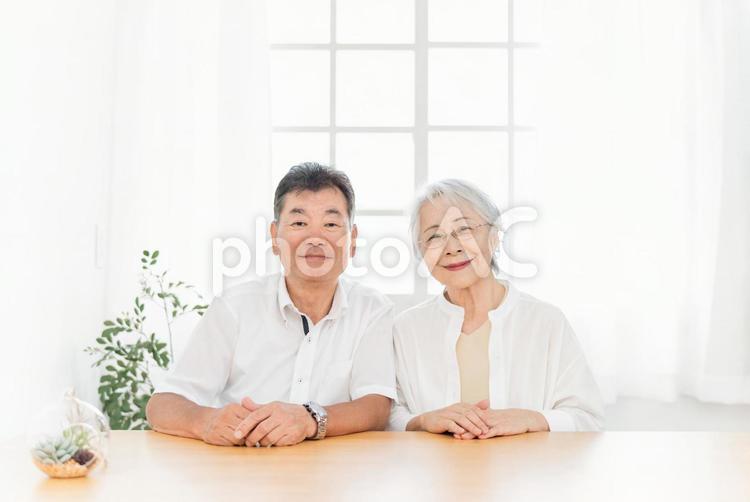 テーブルに座る高齢者夫婦（カメラ目線） 高齢者,シニア,夫婦の写真素材