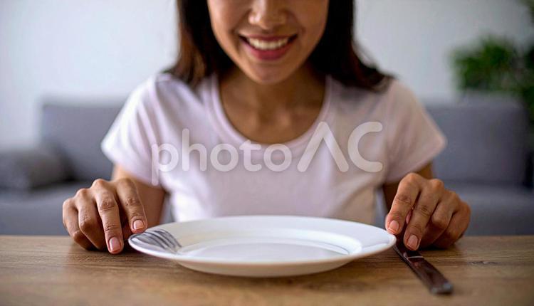 食後、空になったお皿を前に笑顔の女性 満腹,満足,食後の写真素材
