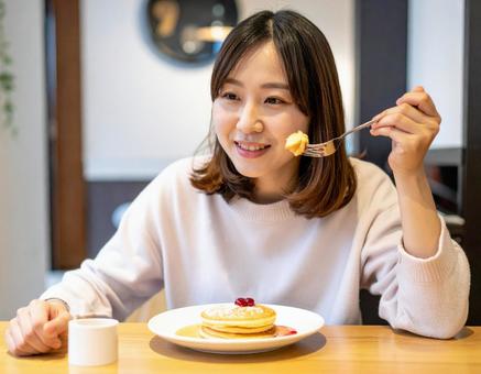 カフェでパンケーキを食べる女性 カフェでパンケーキを食べる女性の写真