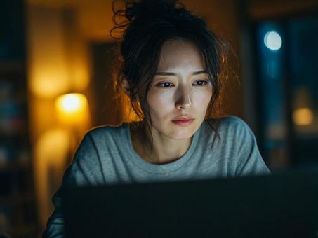 深夜一人でパソコンをする女性 深夜一人でパソコンをする女性の写真