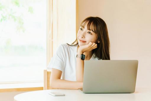 リビングでノートパソコンを使う女性 リビングでノートパソコンを使う女性 女性,パソコン,微笑むの写真素材