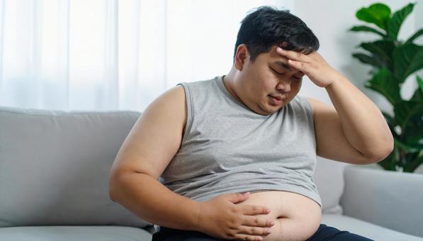 肥満で疲れやすく、額に手をやる男性 肥満で疲れやすく、額に手をやる男性の写真