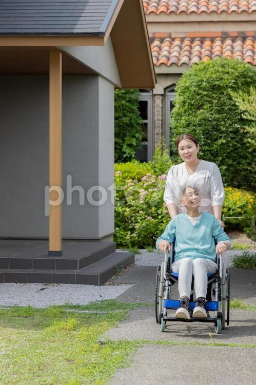 庭で車椅子に乗るシニア女性とヘルパー シニア,車椅子,散歩の写真素材