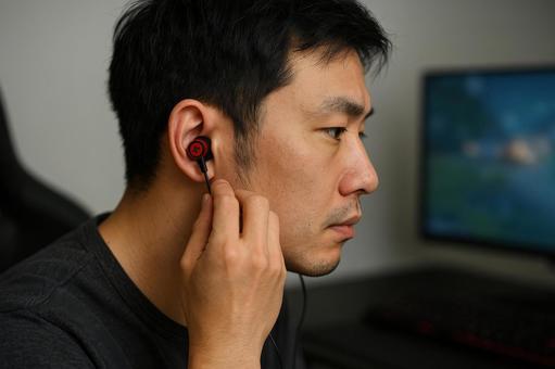 ゲーム中イヤホン装着の男性 ゲーム中イヤホン装着の男性の写真