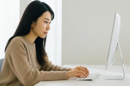 デスクトップパソコンを操作する女性 デスクトップパソコンを操作する女性の写真