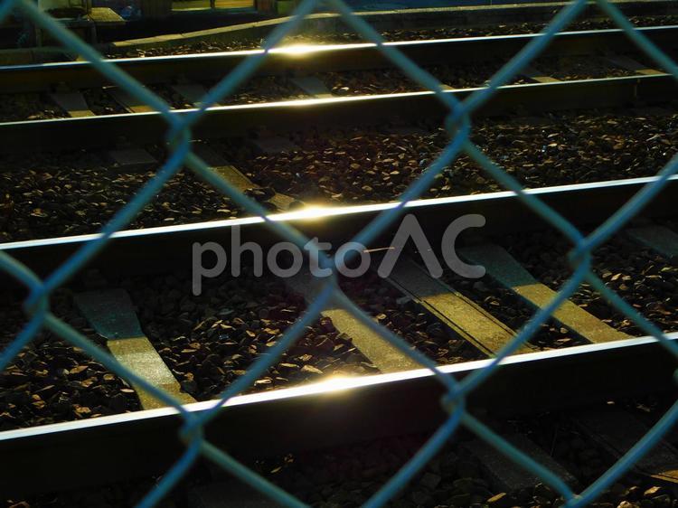 フェンスの向こうで光る線路２本 線路,レール,鉄道の写真素材