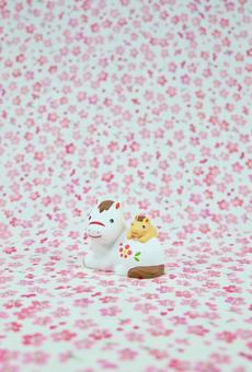 可愛い馬の置物と花柄の背景の年賀状素材の写真