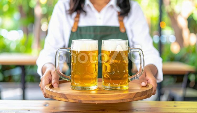 生ビールを客のテーブルに置こうとする店員 ビアガーデン,ビール,生ビールの写真素材