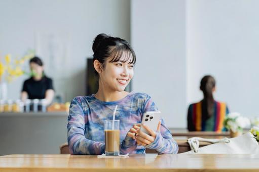 カフェでスマホを使う若い女性 カフェでスマホを使う若い女性の写真