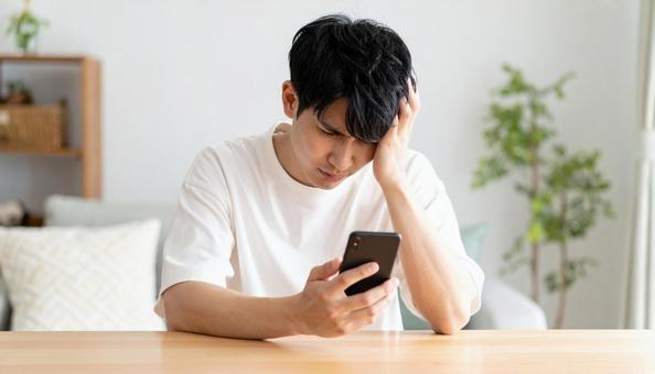 スマホを見て困惑する男性のリアクション スマホを見て困惑する男性のリアクションの写真