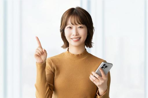 スマホを持って案内をする笑顔の女性 スマホを持って案内をする笑顔の女性 女性,スマホ,笑顔の写真素材