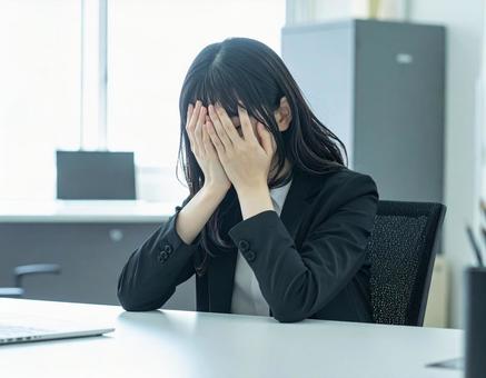 オフィスのデスクで泣いている女性会社員 オフィスのデスクで泣いている女性会社員の写真