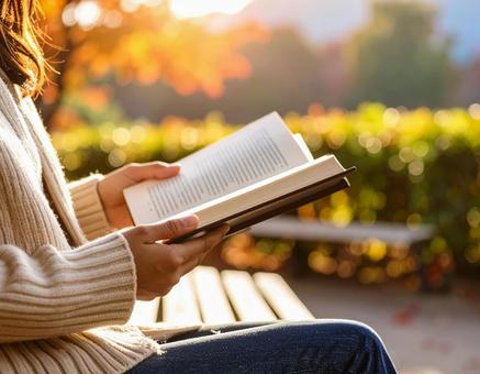 ベンチで本を読む秋のひとときの写真