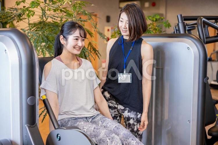 足の筋トレをする女性（レッグエクステンション・笑顔） スポーツジム,脚,運動の写真素材