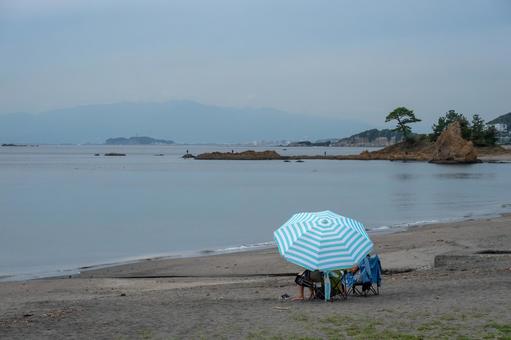 海岸でビーチパラソルを広げ江の島を望む 海岸でビーチパラソルを広げ江の島を望む ビーチ,海岸,beachの写真素材