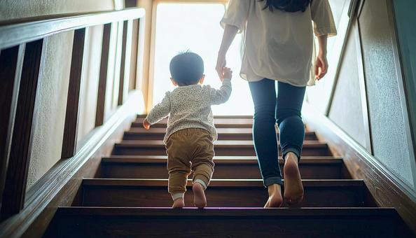 階段を下りるのが楽しい子供と支える母親 階段を下りるのが楽しい子供と支える母親の写真