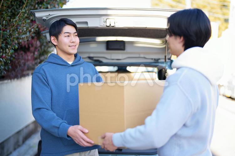 車から引っ越しの段ボール箱を運び出している2人の男性 引っ越し,一人暮らし,男性の写真素材