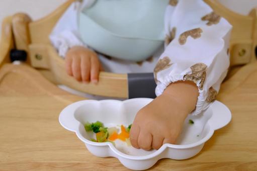 ハイチェアで野菜を手づかみ食べする子ども 手づかみ,離乳食,子どもの写真素材