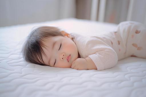 ベッドの上ですやすや眠る赤ちゃん ベッドの上ですやすや眠る赤ちゃんの写真