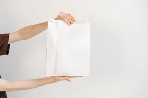 白い紙袋を差し出す手 配達,フードデリバリー,テイクアウトの写真素材