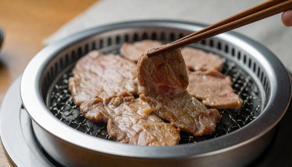 焼肉を鉄板で焼いて箸ですくう 焼肉を鉄板で焼いて箸ですくうの写真