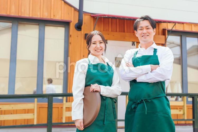 お店の前に立つエプロン姿の男女 カフェ,飲食店,ウェイトレスの写真素材