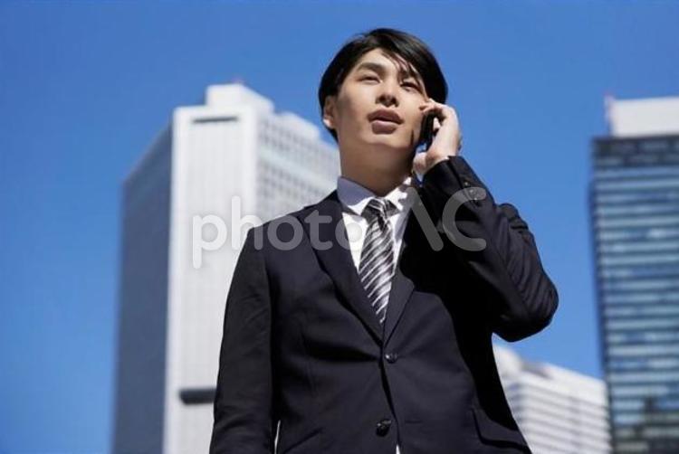 オフィス街で電話をするビジネスマン ビジネスマン,男性,スマートフォンの写真素材