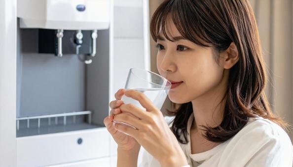 ウォーターサーバーで水を飲む日本人女性 ウォーターサーバーで水を飲む日本人女性の写真