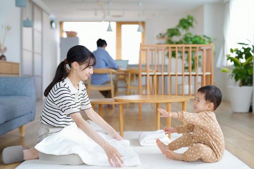タオルを畳みながら子供を見る母 タオルを畳みながら子供を見る母の写真