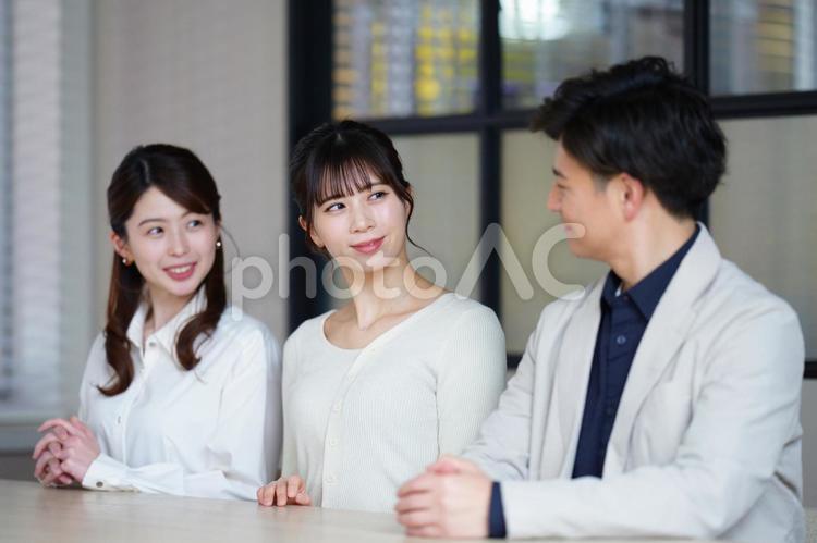 横並びで座る笑顔の男女3人 男女,話す,聞くの写真素材